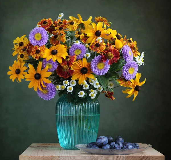 Kytice z pěstovaných květin do vázy a švestky. — Stock fotografie