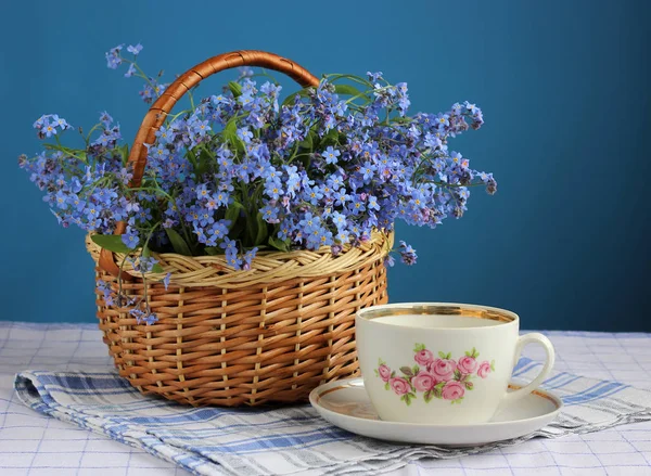 Basket of forget-me-nots and retro Cup. — Stock Photo, Image