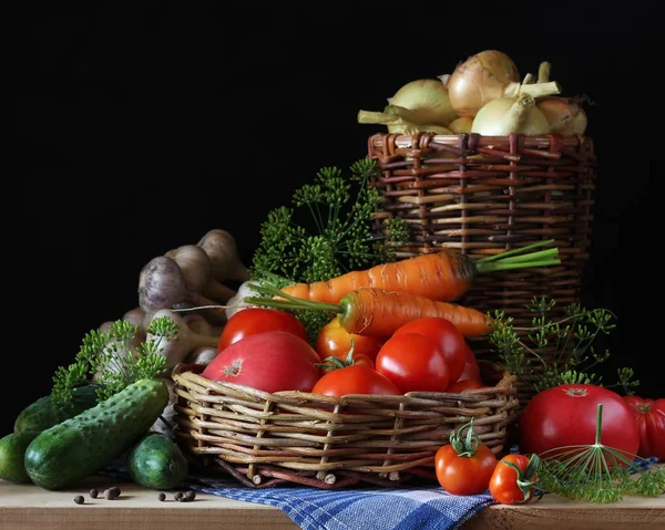 Massa färska grönsaker i korgar och på bord på mörka bakgr — Stockfoto