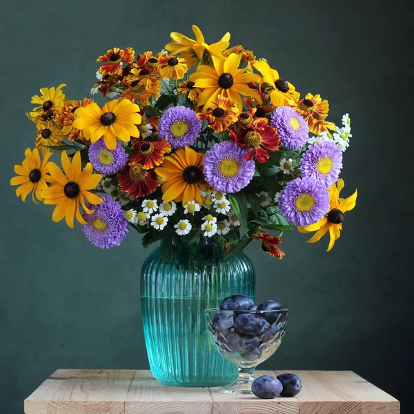 Осенний натюрморт: цветы и сливы . — стоковое фото