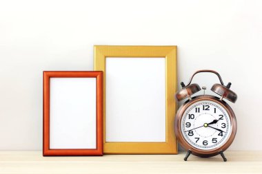 Boş resim çerçeveleri ve hafif bir arka plan üzerinde bir çalar saat.