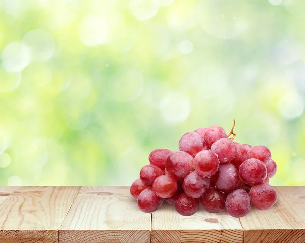 Red grapes on a wooden table top on blurred nature background. — Stock Photo, Image
