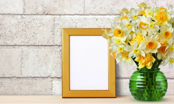Marco de oro vacío para la foto y el ramo de narcisos amarillos en un — Foto de Stock