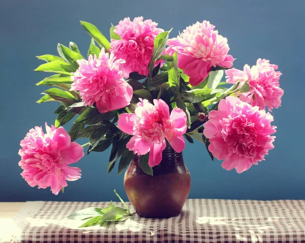 Ramo de peonías rosadas con hojas en una jarra de barro . —  Fotos de Stock