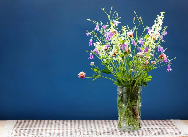濃い青の背景にガラスの花瓶の中の野生の花の花束 — ストック写真