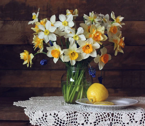 Buquê de narcisos amarelos e um limão na mesa . — Fotografia de Stock