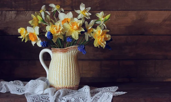 Garden yellow daffodils and blue Muscari in a jug. — Stock Photo, Image