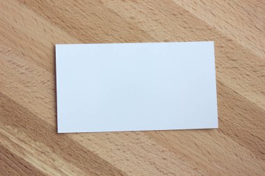 Model, üzerinde boş bir kağıt kartvizit olan şablon, doğal ahşap arka plan, üst manzara. Metnin ya da resmin için boşluk.