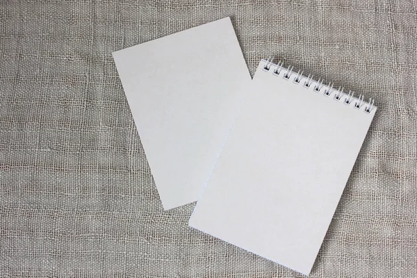 Notepad with an empty cover on a light linen fabric, top view. the layout template for the installation of Your drawing or text.