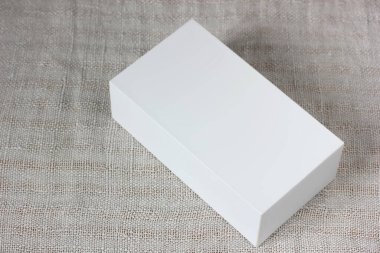 Gri kumaş arka planda beyaz karton kutu, üst manzara. Metin veya deseninizi yüklemek için şablon, düzen.