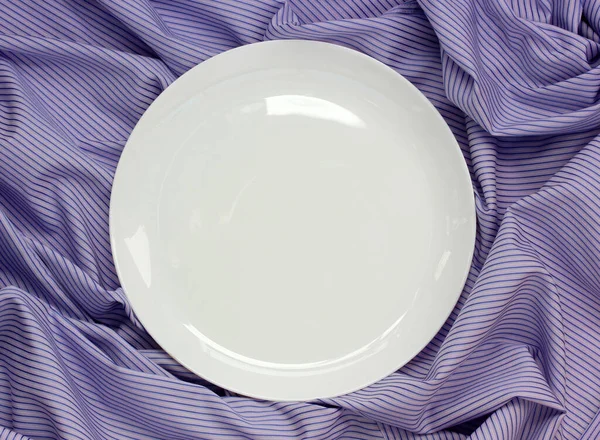 紫色の縞模様のテーブルクロスに空の白い磁器プレート 上からの眺め 製品を実装するためのテンプレート レイアウト スペース — ストック写真