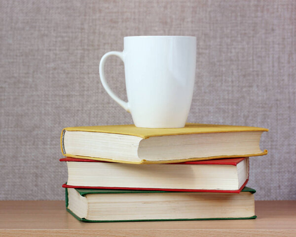 white mug and books on the table. space for Your text or pattern.
