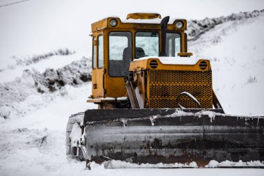 Sarı buldozer kışın sokakta, kar yağışı ve kar yamaçlarında