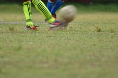 Futbolcu futbol topunu tekmelemek için koşuyor.