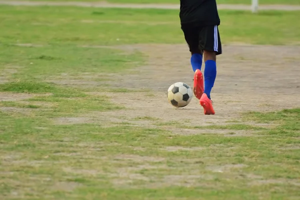 サッカー選手は現場でサッカー練習中にサッカーボールをキックするために実行されます — ストック写真