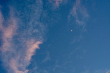 Mavi gökyüzü ile geç akşam kırmızı nadir bulutlar üzerinde ay.