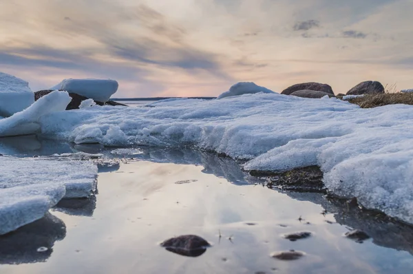 Sunset winter lake shore landscape with stones, snow and ice. Closeup, Ladoga lake, selective focus