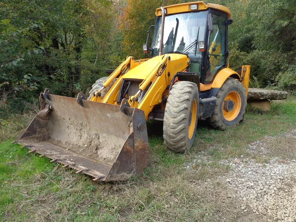 Bulldozer en el lado de la carretera cerca del bosque — Foto de Stock