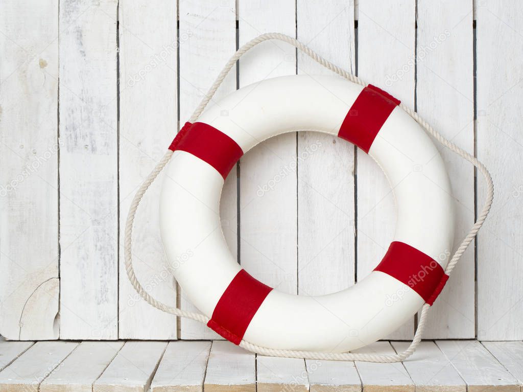 Lifebuoy on white wooden background. Sea style composition.