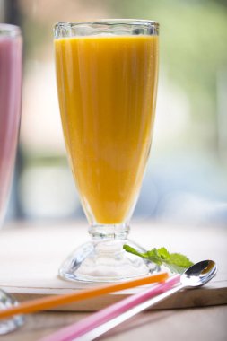 Meyve yeşili smoothie. Yaz ve tropik hava. Soğuk harmanlanmış içecek, nane, çilek ve mango suyu. Pencereye yakın, sarı ve pembe renk.