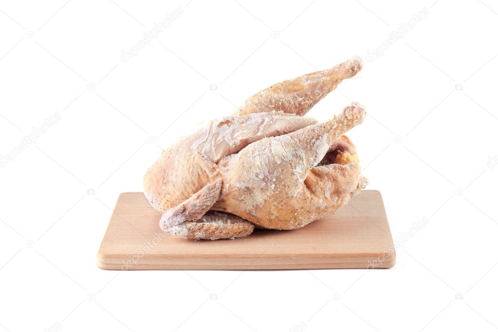 Frozen chicken carcass on a wooden chopping board
