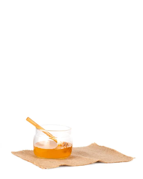 Fresh liquid honey in a glass jar and a wooden spoon — Stock Photo, Image