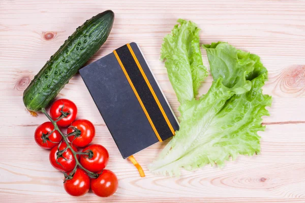 Légumes mûrs et cahier sur bureau en bois — Photo