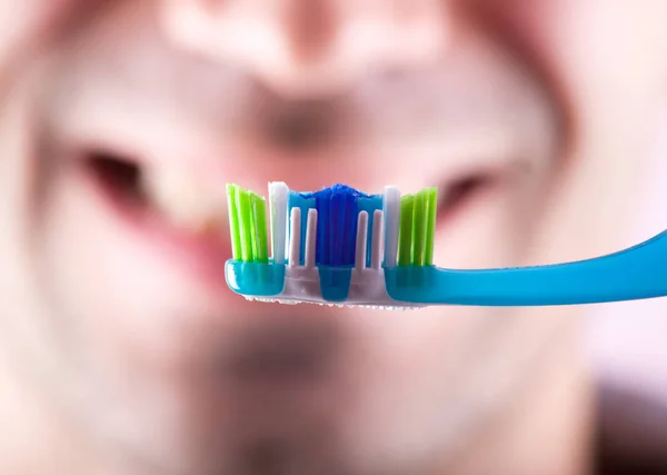 Νέα οδοντόβουρτσα στο φόντο του προσώπου. — Φωτογραφία Αρχείου