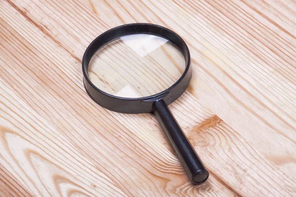 Lupa en un tablero de madera . — Foto de Stock