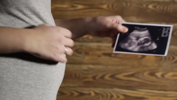 妊娠中の女性は写真を手に保持します。 — ストック動画