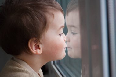 Çocuk pencereden görünüyor