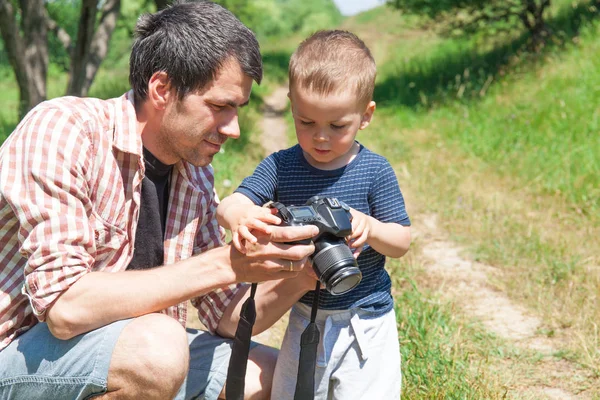 Father and son with camera in nature