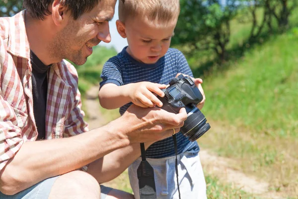 Father and son with camera in nature