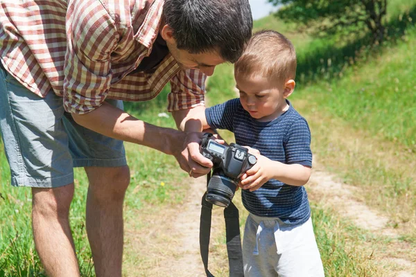 Father and son with camera in nature
