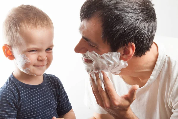 Dad teaches his son to shave.
