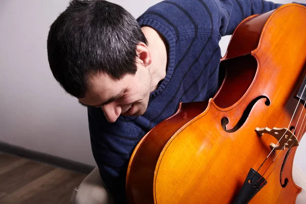 Man with cello in room with wall — Stock Photo, Image