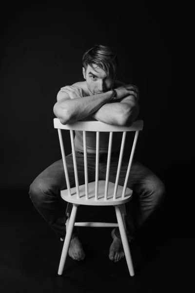 Muscular e ajuste jovem fisiculturista fitness modelo masculino posando na cadeira. Foto em preto e branco . — Fotografia de Stock