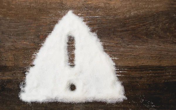 Sign of warning attention made of granulated sugar. A conceptual photo illustrating the harm from consuming white refined sugar and products containing it — Stock Photo, Image