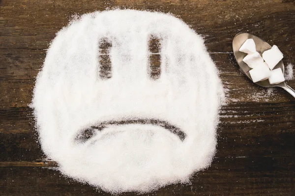 Toz şeker ile yapılan bir üzücü gülen yüzü. Şeker ve tuz gibi lezzet katkı maddeleri olan bağımlılığını yeme zarar resmi gösterir.