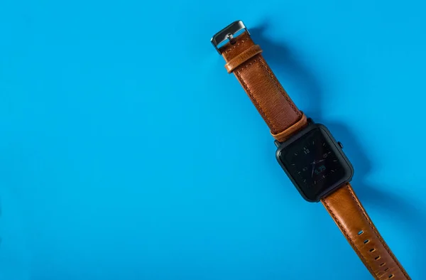 Pastel renkli bir arka plan üzerinde deri kayışı ile akıllı izle