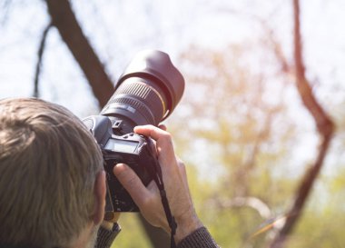 Fotoğrafçı telefoto lens ile fotoğraf makinesi ile. Çekim uzak nesneleri