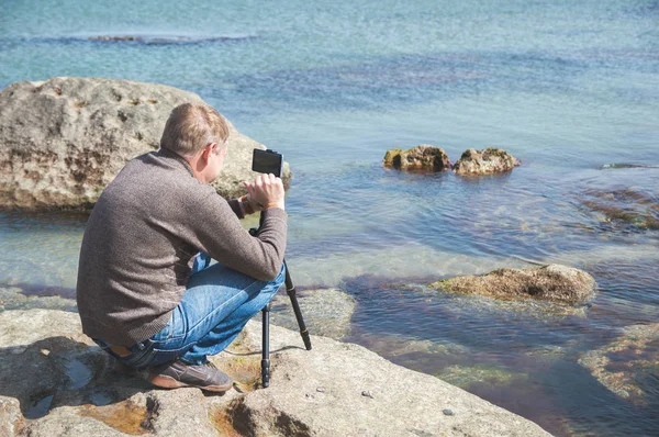 Adam telefonda bir deniz kayalık sahil üçayağa monte fotoğraf çeker