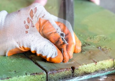 İşçi tutan ve bir ahşap tahta bir çivi tıkanma eldiven