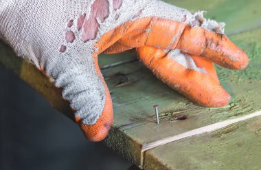 İşçi tutan ve bir ahşap tahta bir çivi tıkanma eldiven