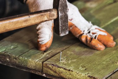 İşçi tutan ve bir ahşap tahta bir çivi tıkanma eldiven