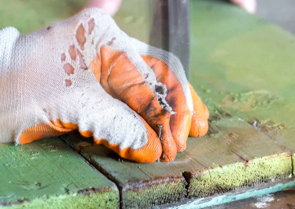 İşçi tutan ve bir ahşap tahta bir çivi tıkanma eldiven