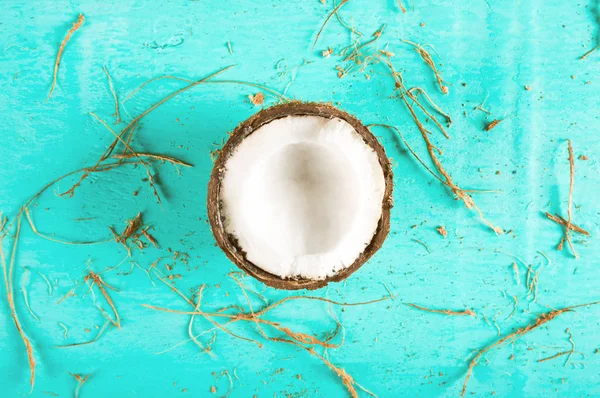 Die Hälfte der gehackten Kokosnuss auf blauem Hintergrund mit Schale — Stockfoto