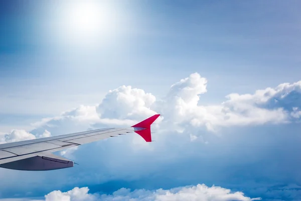 Ciel nuageux et aile de l'avion rouge vu à travers la fenêtre sur aircr — Photo