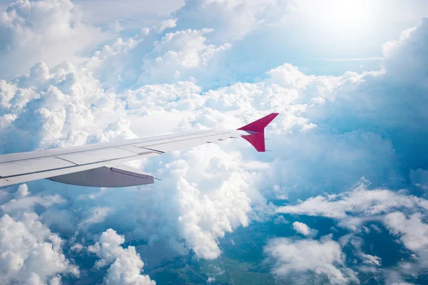 Ciel nuageux et aile de l'avion rouge vu à travers la fenêtre sur aircr — Photo