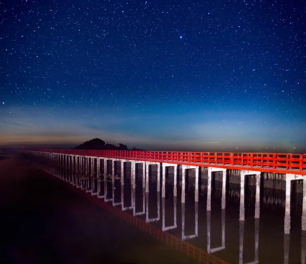 red bridge in the night sky with star on top of the sea